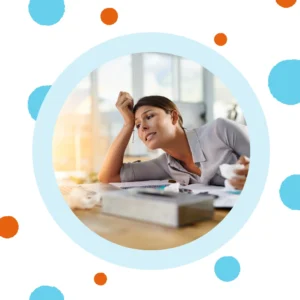 A woman holds her head and leans while at her desk. 