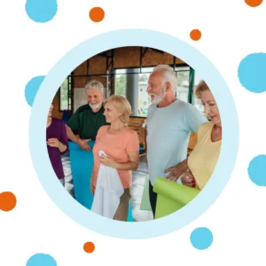 Older people chat in a yoga classroom.