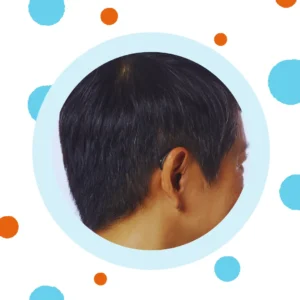 A black hearing aid sits behind a person's ear. 