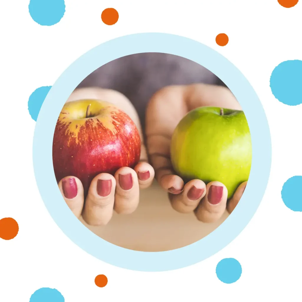 Hands hold a red apple and a green apple.