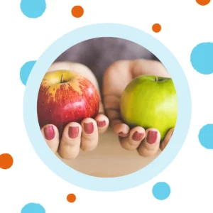 Hands hold a red apple and a green apple.