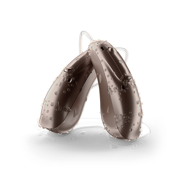 Two sandalwood colored waterproof receiver-in-canal hearing aids, known as The Security by Injoy Hearing, with water droplets on them.