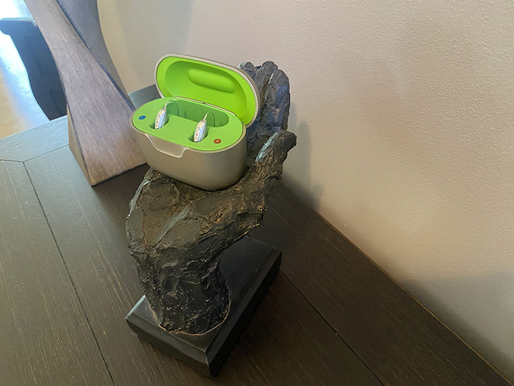 Phonak hearing aids in their charging case sit on a table.