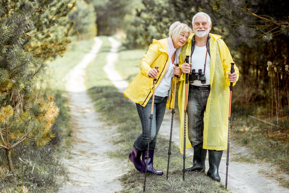 mature couple hiking in raincoats enjoying the comfort of waterproof hearing aids