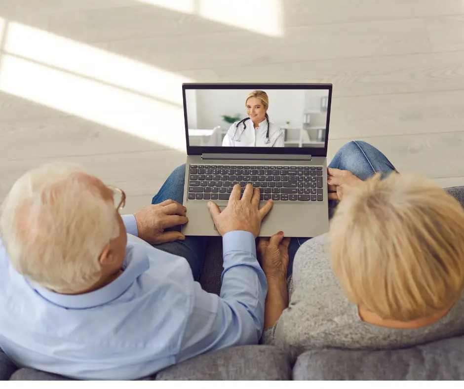 An older couple has a telehearing appointment on a laptop. 