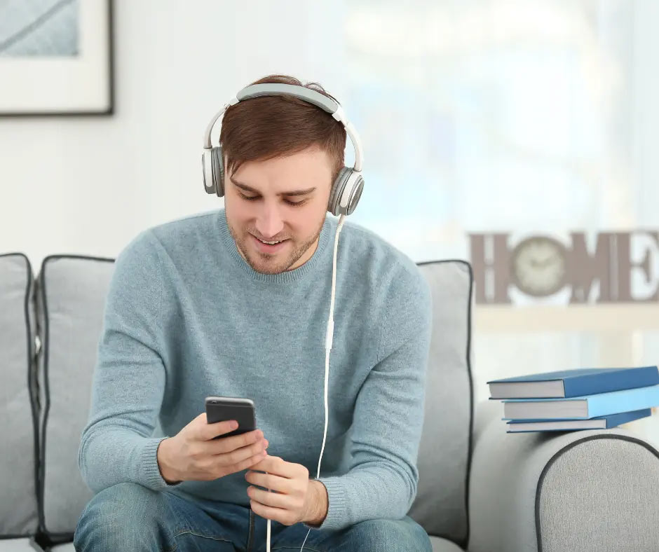 A man wearing headphones looks at his phone.