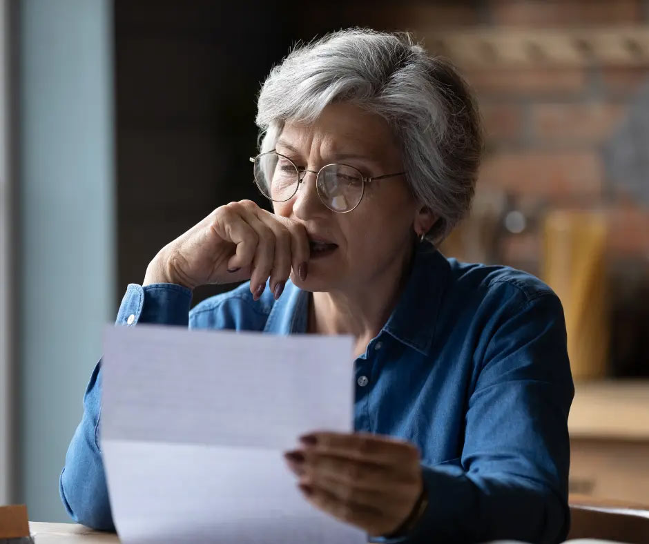 A woman looks stressed out as she reads a piece of paper. 