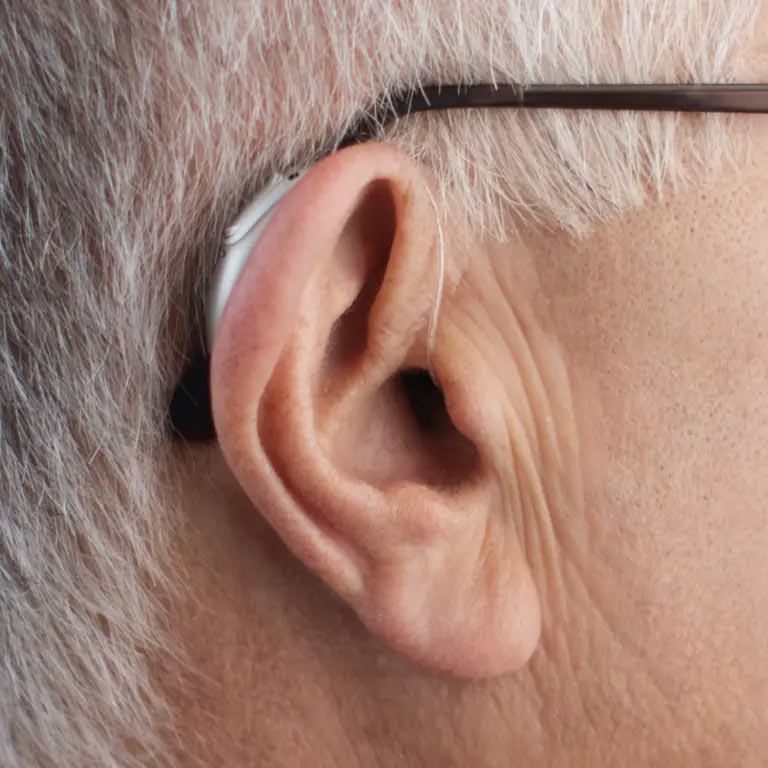 A grandfather wears a Phonak hearing aid behind his right ear.