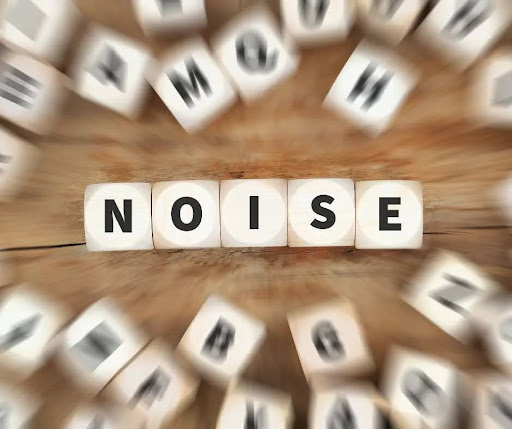 Scrabble letters spell out the word “noise” in the middle of other blurry letters.